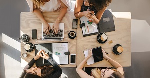 top view of table with employees sitting working on computer and tablet